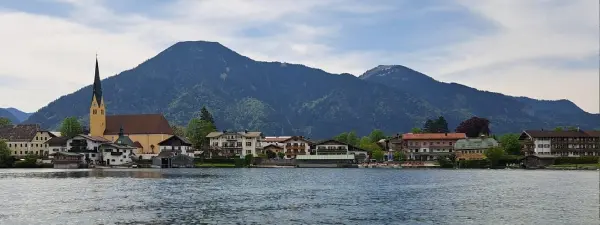 Tegernsee mit Seepromenade und bewaldeten Bergen im Hintergrund